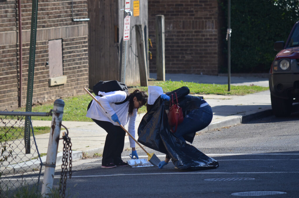 DSC_7260 Two people picking up litter on a street, promoting community cleanliness and environmental responsibility.