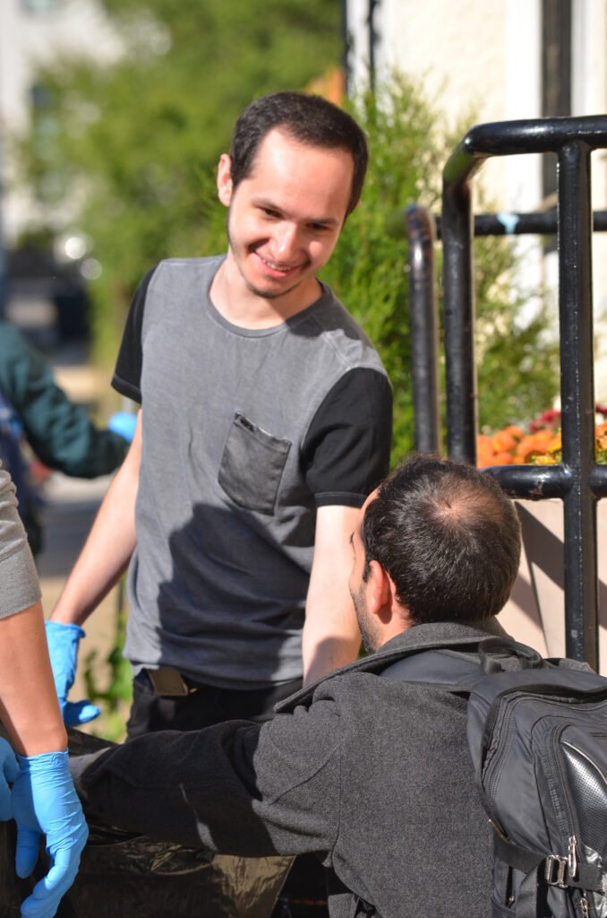 DSC_7282 Person smiling and helping another person outdoors in a friendly exchange.