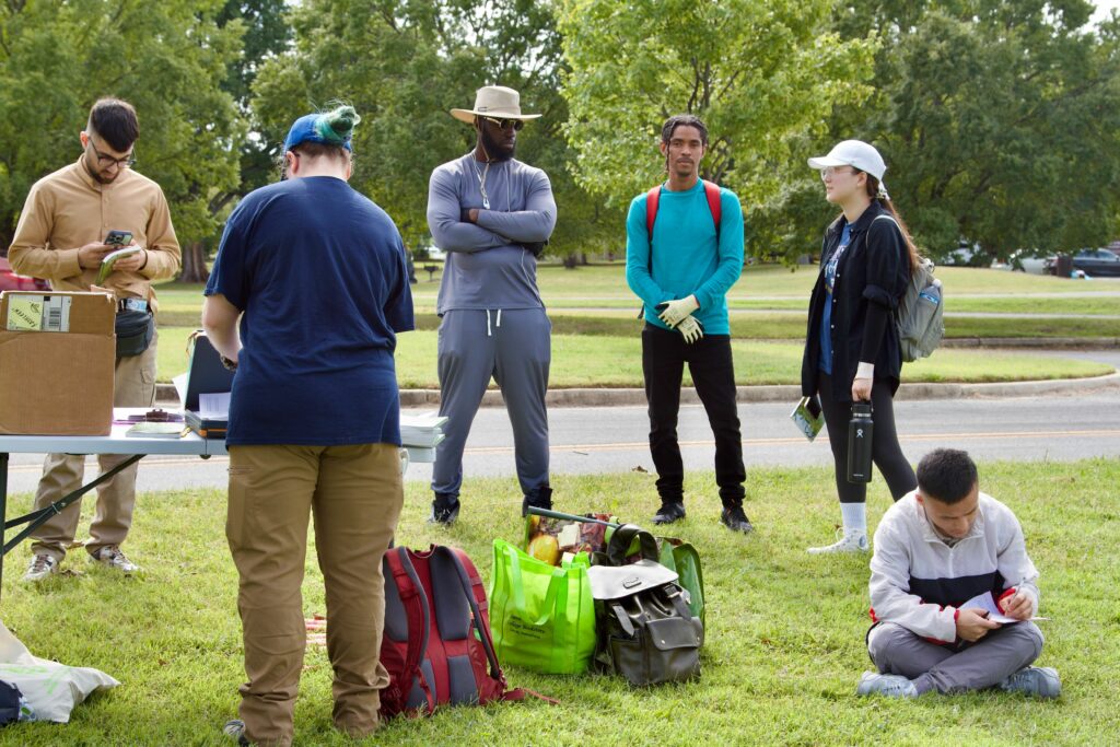 IMG_2857 Group of people preparing for a community cleanup event in a park, with equipment and supplies on the grass.