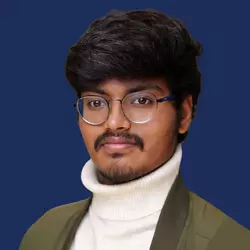 Portrait of a young man wearing glasses and a turtleneck sweater against a blue background.