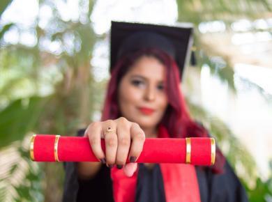 Types of MBA Degree: Which One Is Right for You 24 Graduate holding diploma in focus, wearing cap and gown with blurred background, symbolizing achievement and success.