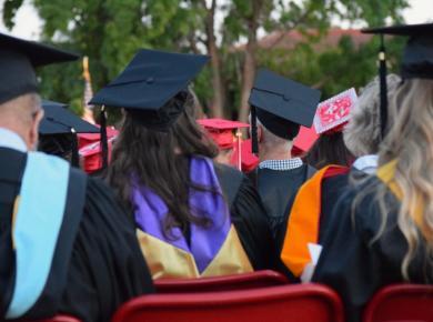 MBA vs Master’s How do They Differ 22 Graduates in caps and gowns seated outdoors during a commencement ceremony.