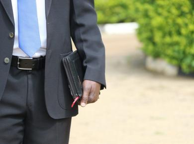 How to Find a Job After College: Increase Your Chances of Landing Your Dream Job 29 Man in suit holding a book and wearing a blue tie on a sunny day.