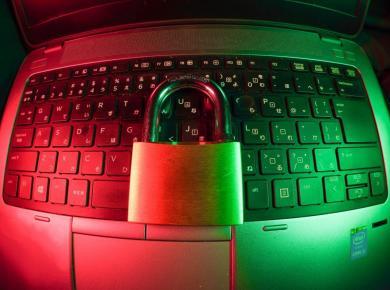 Cyber Security Careers: How to Become an Information Security Analyst 16 Padlock on a laptop keyboard, symbolizing cybersecurity and data protection, with red and green lighting.