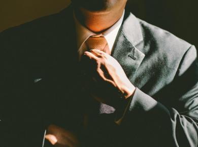 13 Best MBA Jobs: Descriptions and Salary Information 10 Man adjusting tie in business suit, showcasing professional attire and confidence.