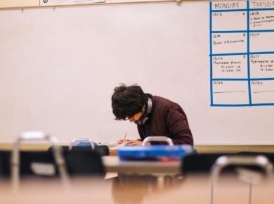 Early Action vs. Early Decision: Which to Choose? 7 Student studying alone in a classroom with a whiteboard calendar.