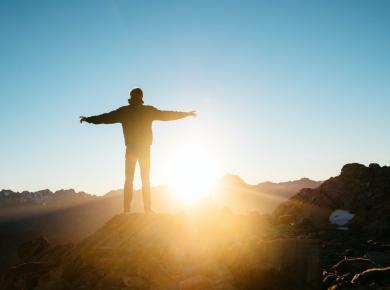 What Is a Gap Year: A Period of Opportunities or Risks? 41 Person standing on a mountain peak at sunrise, arms stretched wide, embracing freedom and nature's beauty.