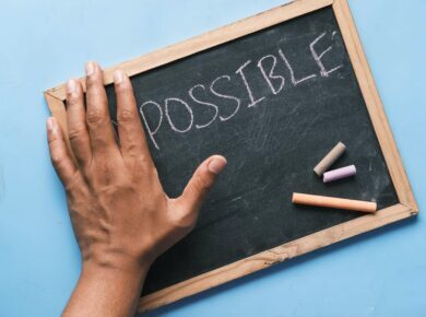 A List Of Simple Ideas To Improve Students Motivation 27 Hand covering im on blackboard revealing possible, with colorful chalk, symbolizing positivity and potential.