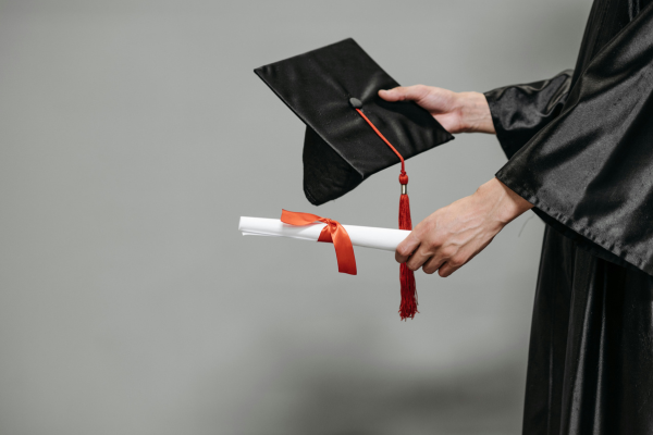 graduate holding diploma and graduation cap