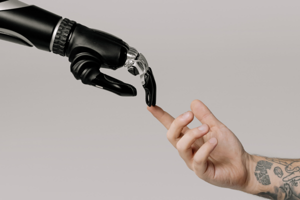 Robot hand and human hand touching fingers — artificial intelligence, human-robot collaboration, and AI jobs of the future concept.