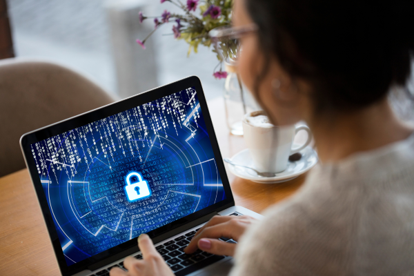 Cybersecurity analyst working on a laptop with digital lock icon — AI and cybersecurity protection concept.