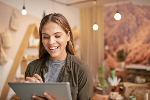 Smiling student building an online resume and personal brand using a tablet in a creative workspace.