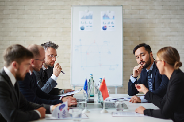 Business professionals in a policy meeting, discussing charts and data, highlighting analytical roles in political science careers.