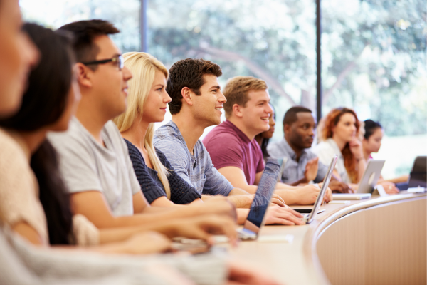 College students in a lecture hall attending a class on different types of business administration degrees.