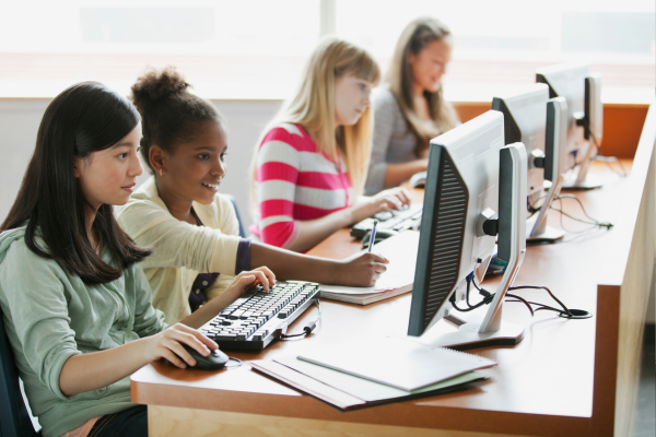 Young students working together on desktop computers in a classroom setting, focused and engaged in a learning activity.