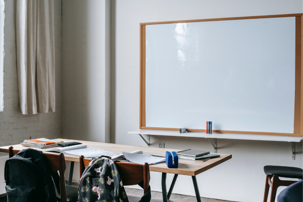 Empty classroom with desks, chairs, a whiteboard, and stationery, creating a ready-to-learn environment.