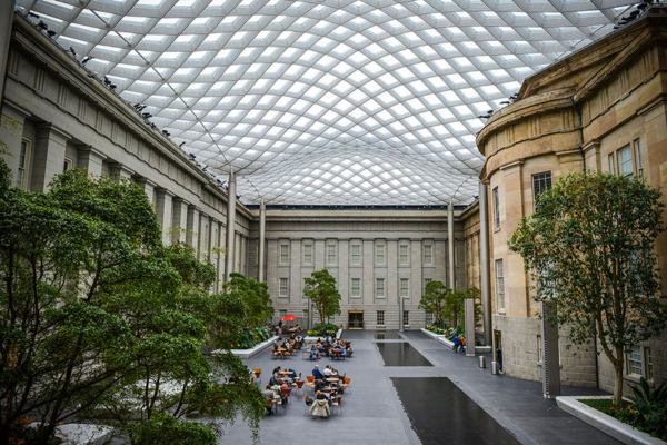 Wide view of the Kogod Courtyard at the National Portrait Gallery in Washington, D.C., with people studying beneath the modern glass canopy. © FotoBriceno LLC, courtesy of the National Portrait Gallery.