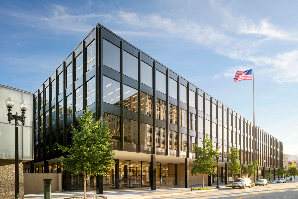 Exterior view of the Martin Luther King Jr. Memorial Library in Washington, D.C., featuring modern glass architecture and an American flag under a clear blue sky