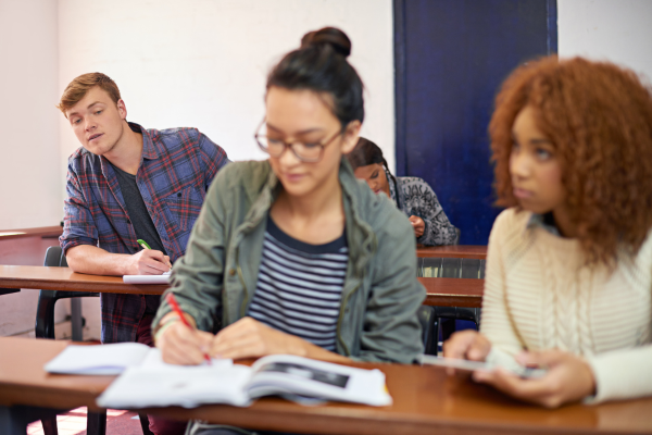 Students in a classroom taking notes, focused and engaged in learning.