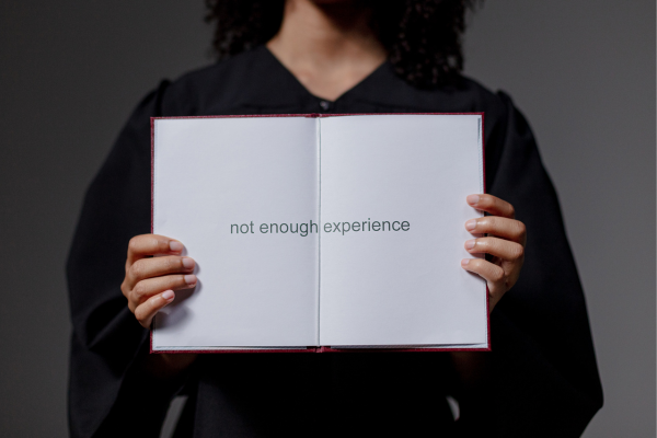 Graduate holding a blank diploma with not enough experience text, highlighting job market challenges for new grads.