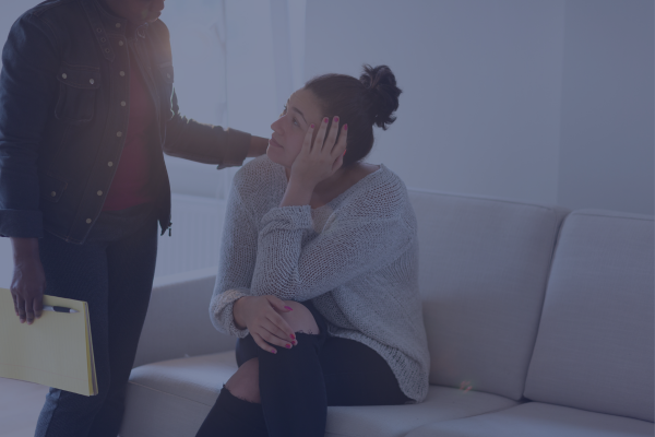 A supportive friend providing mental health support to their friend sitting on a coach.