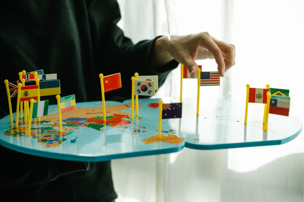 Colorful map with miniature country flags, a hand adjusting the USA flag. Perfect for global education and travel themes.