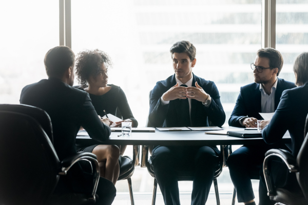 Business team engaged in discussion around a conference table, with a cityscape visible through large windows.