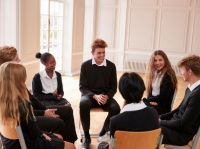 How Student Clubs Can Help Boost Your Career Readiness 8 Members of student clubs in school uniforms sitting in a circle, engaged in a group discussion in a bright classroom.
