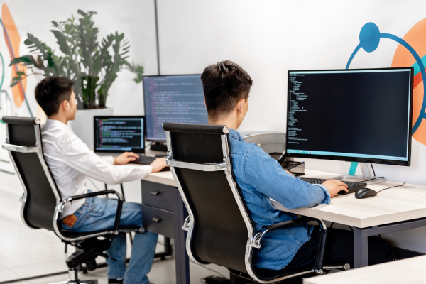 Developers coding in modern office setting with multiple monitors.