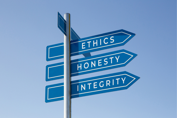 Signpost with arrows pointing to ethics, honesty, and integrity against a clear blue sky.