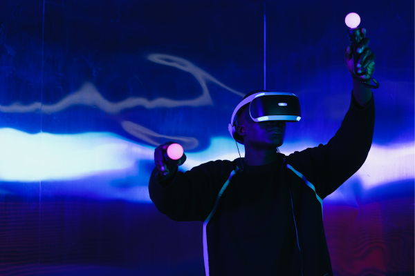 Person using virtual reality headset and controllers in a neon-lit room for immersive gaming experience.