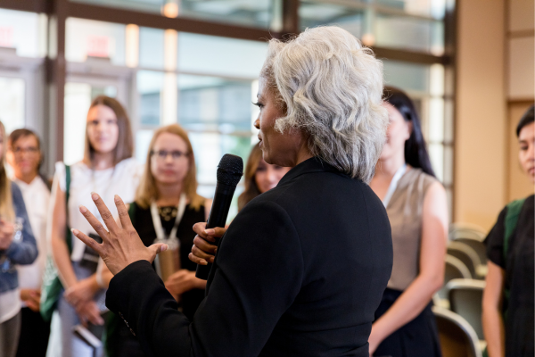 A business leader addressing a group with a microphone, highlighting the intersection of business and politics in shaping today’s conversations.
