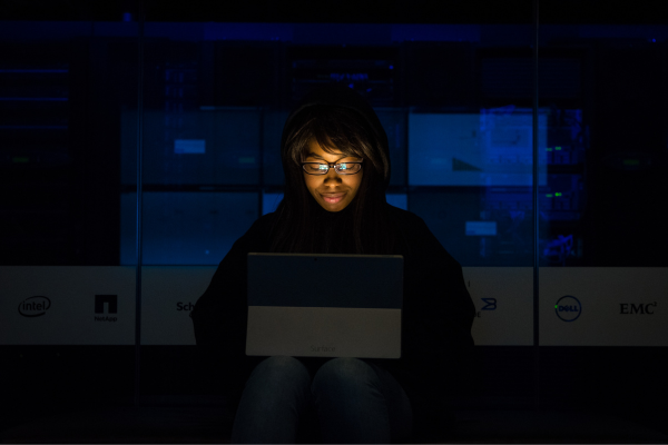 Woman working on a laptop in a server room deciding between cloud computing vs. software engineering