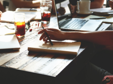 How Lifelong Learning Is Reshaping the Workforce 17 A person engaged in lifelong learning, writing notes on paper while studying in a coffee shop.