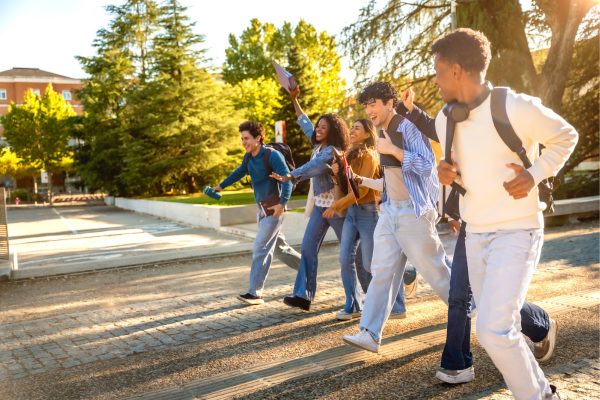 Innovation in Higher Education: How BAU Prepares Students 13 Group of diverse students joyfully running outdoors with backpacks, embracing university life and friendship in sunny weather.
