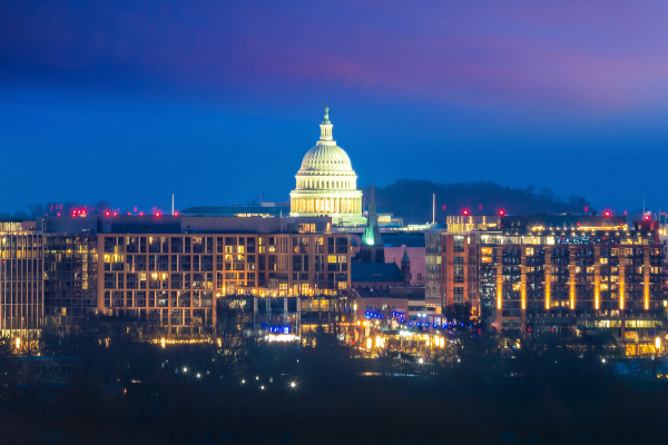 Night view of the U.S. Capitol building in Washington D.C. illuminated against a deep blue sky.