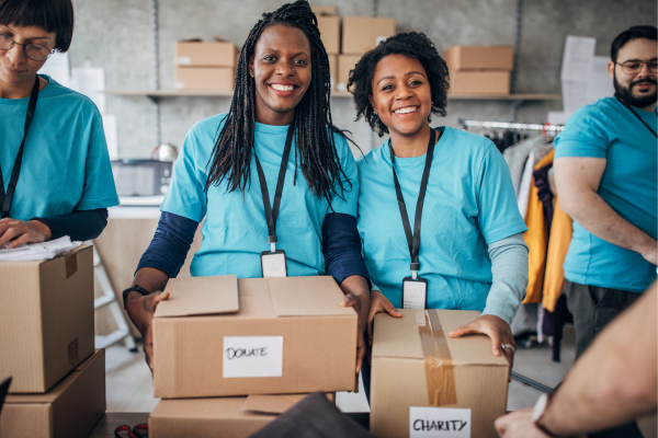 The Rise of Social Entrepreneurship: Combining Business with Purpose 7 Volunteers in blue shirts organize donation boxes labeled Donate and Charity in a community center.