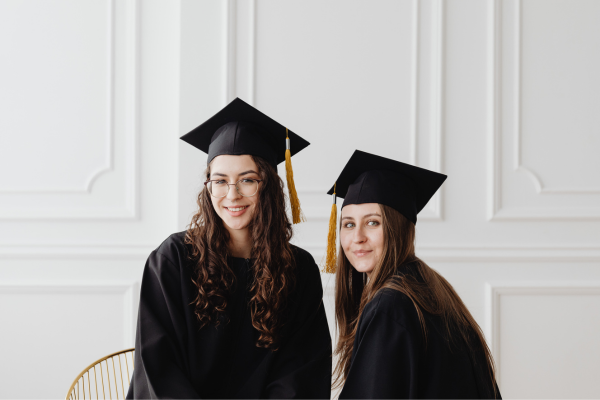 Global Career Skills: 7 Key Skills Employers Expect from International Graduates 11 Two graduates in caps and gowns smiling, celebrating their achievement indoors.