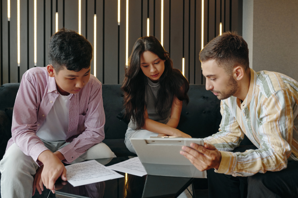 Business Analyst Jobs in Global Demand: Skills, Careers, and Opportunities 7 A business analyst explains different business analyst jobs to two young individuals using a clipboard and documents in a modern office.