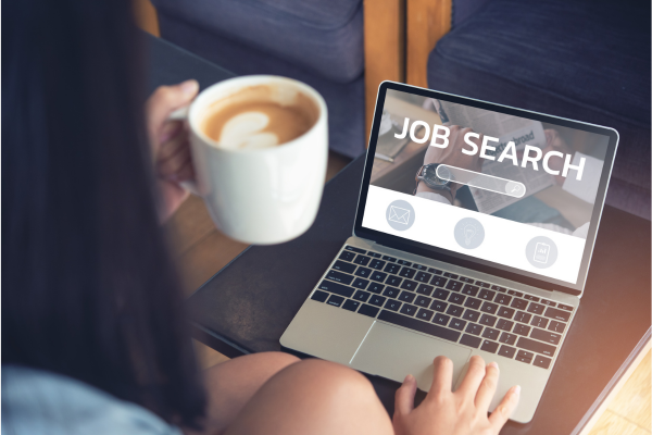 The Power of Global Alumni Networks: How International Connections Boost Career Success 5 Person holding coffee, using laptop for job search on a certain portal, showing importance of global alumni networds.