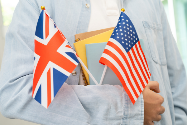 From Basic to Advanced: How to Master English Grammar in the U.S. 8 Person holding UK and US flags with notebooks, symbolizing international education and cultural exchange.