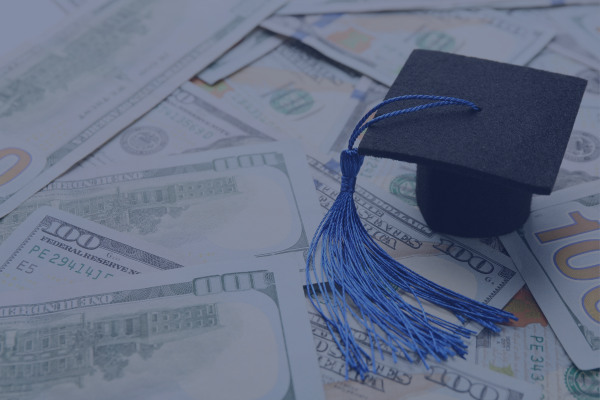 Graduation cap on scattered dollar bills, symbolizing student loans and university costs.