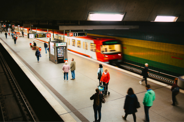 Is Debt-Free Education Possible in the United States? 7 People walking on a subway platform with a train in motion, captured in a vibrant underground station scene.