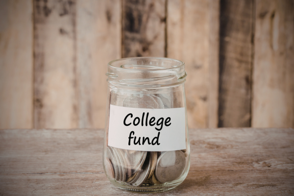 Is Debt-Free Education Possible in the United States? 6 Jar labeled College fund filled with coins on a wooden surface, symbolizing saving for education.