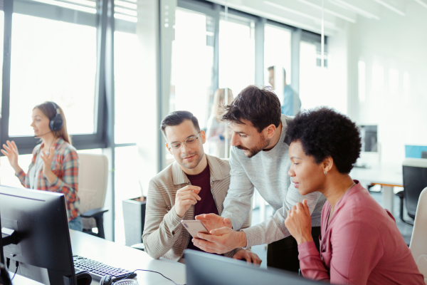 Cybersecurity Management: Why a Master's Degree is the Key to Senior Executive Roles 8 Team collaborating in modern office, viewing a smartphone, and discussing ideas, enhancing productivity and teamwork.