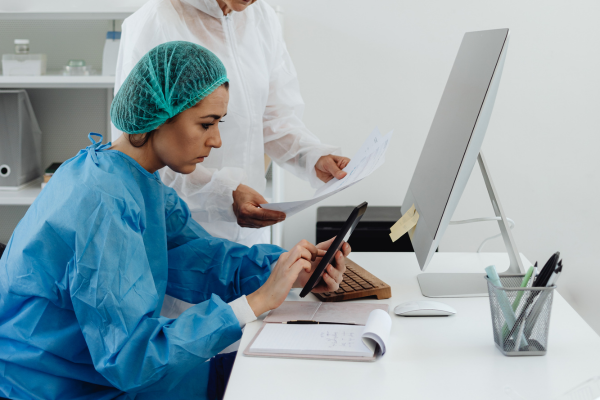 Popular STEM Degrees in 2026: The Ultimate Guide for International Students 8 Medical professionals in protective gear reviewing documents and using a tablet at a desk in a clinical office.