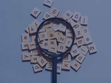 How to Improve Your English Vocabulary Quickly: Intensive ESL for Beginners 47 A magnifying glass over wooden letter tiles representing search and keywords on a neutral background.