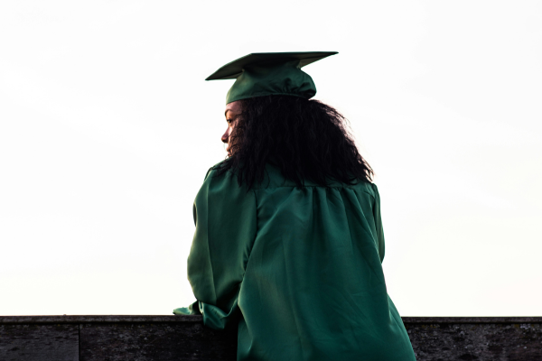 Why Studying in Your Hometown is the Smartest Financial Move in 2026 8 Graduate in green cap and gown gazes into the distance, symbolizing achievement and future possibilities.