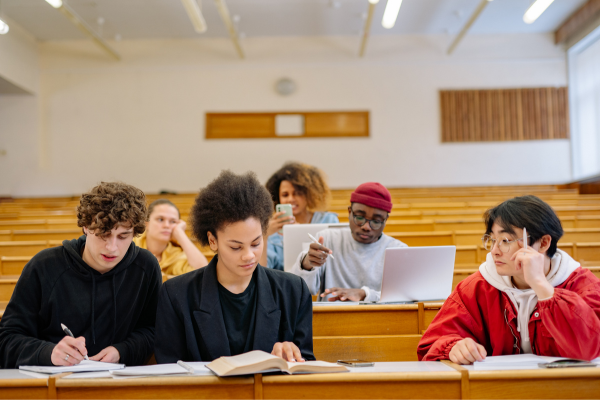 Is Your Degree Worth the Cost? Understanding the ROI of Education in the US 9 Students studying and collaborating with books and laptops in a lecture hall.