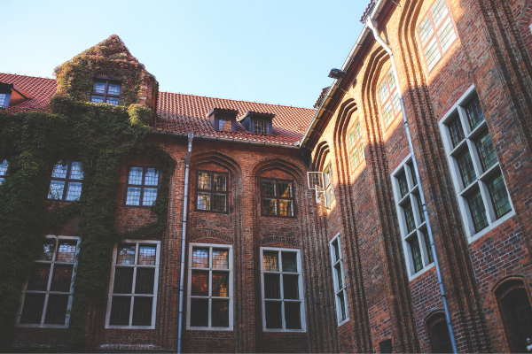 Is Your Degree Worth the Cost? Understanding the ROI of Education in the US 10 Historic brick building with arched windows, ivy-covered walls, and sunlight illuminating the facade.